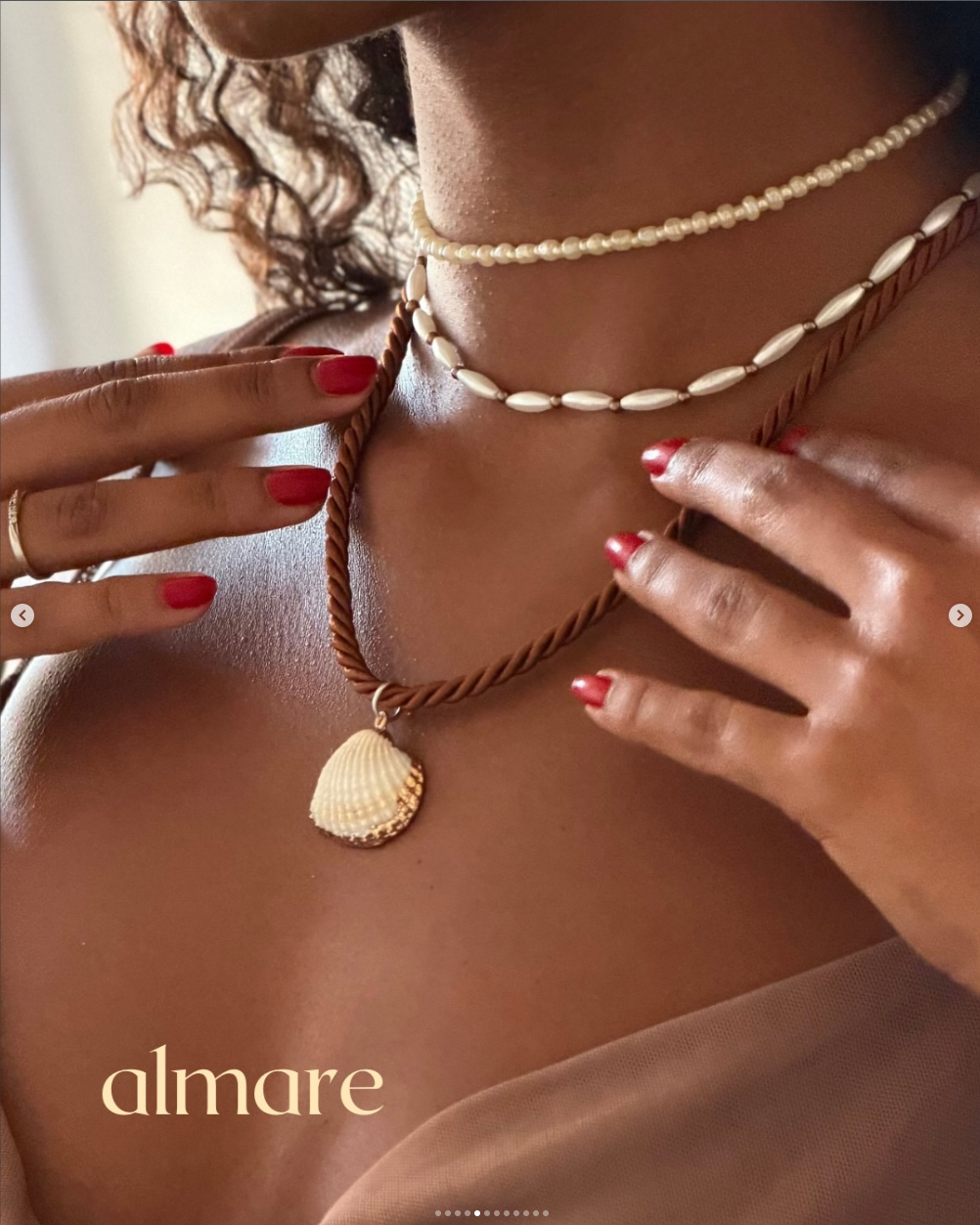 Close de colares almare com pingente de concha e mãos com esmalte vermelho