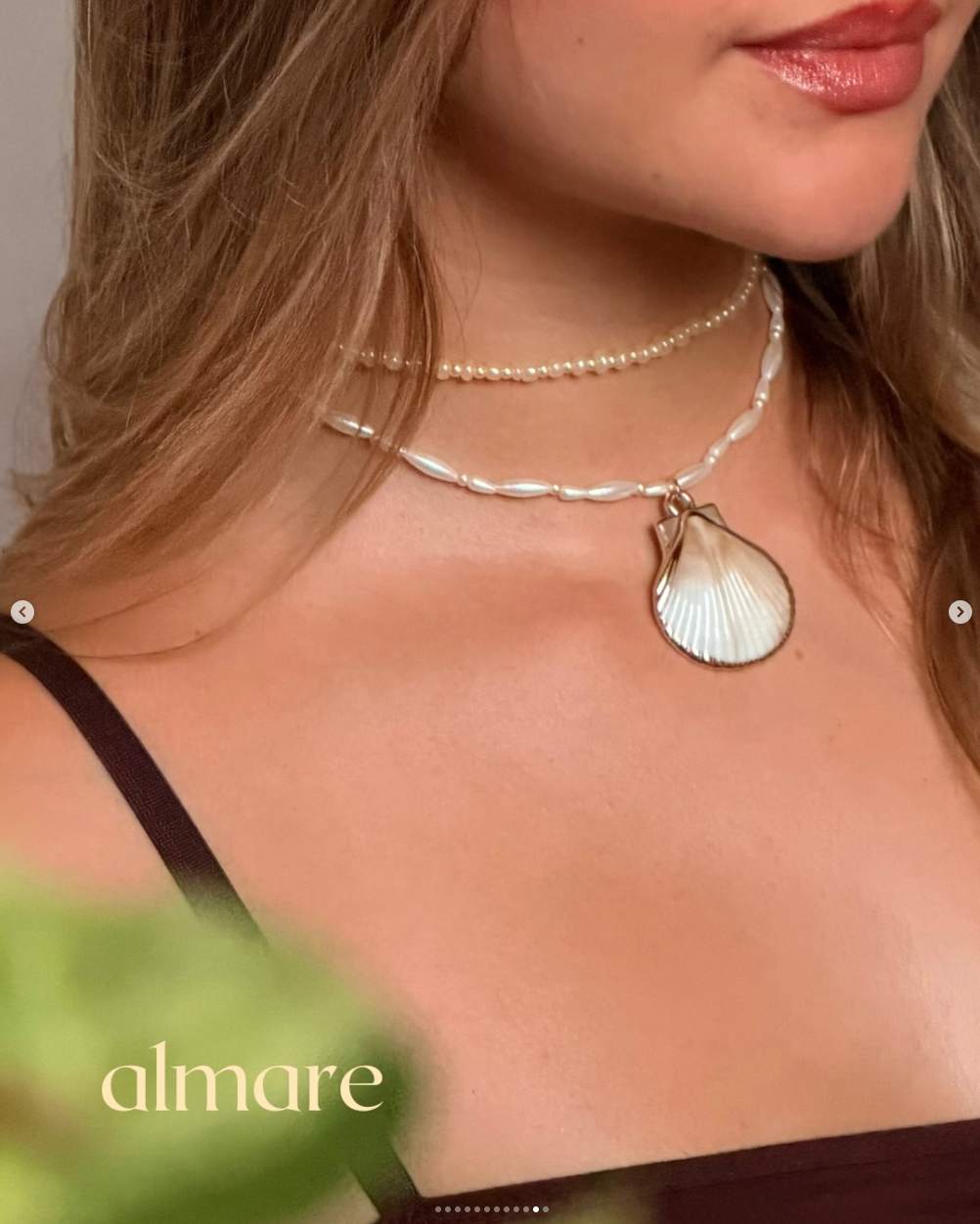 Close de colar almare dourado com pingente de concha sobre vestido marrom